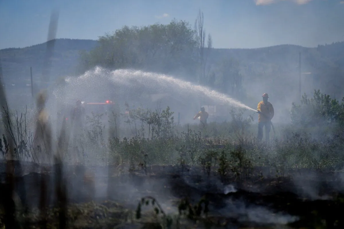 Firefighters battle a grass fire on an acreage behind a residential property in Kamloops, B.C., June 5, 2023. (The Canadian Press/Darryl Dyck)