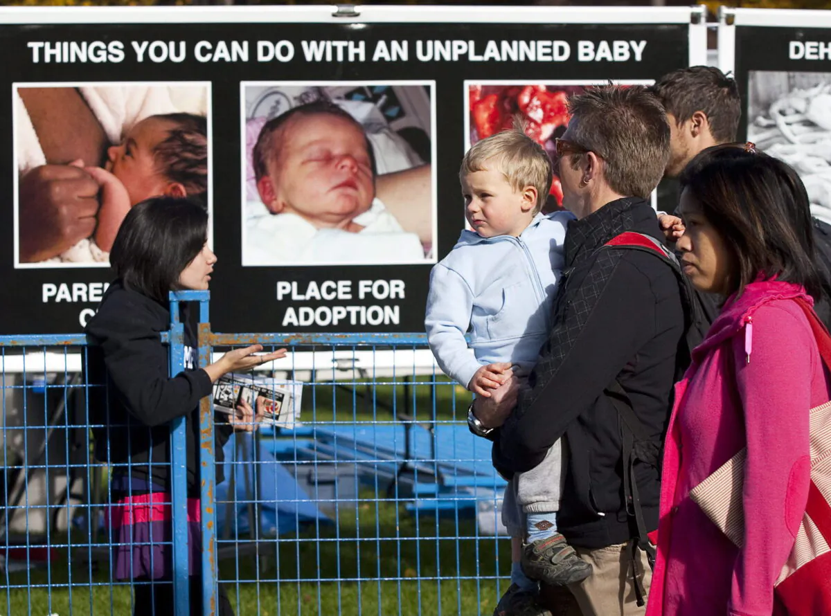 A family walks past a pro-life display erected by members of the Campus Pro-Life student group on the University of Calgary campus in Calgary on Sept. 27, 2010. (The Canadian Press/Jeff McIntosh)