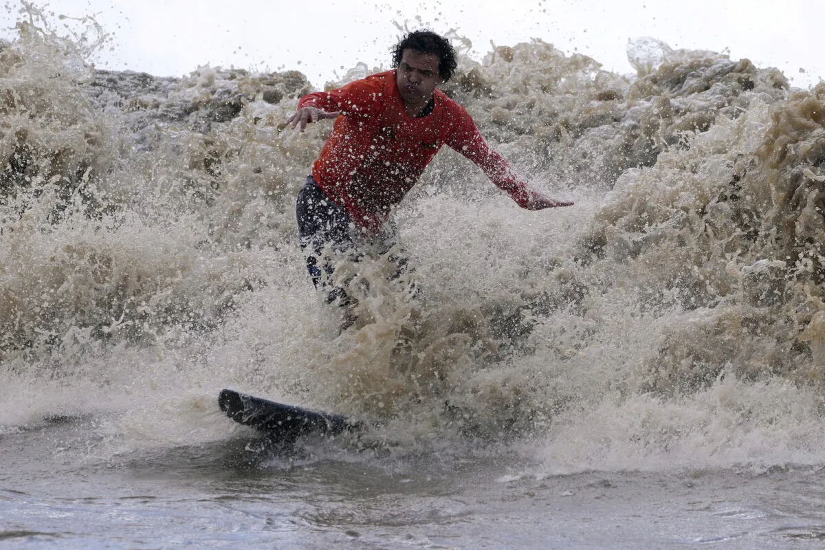 Brazilian surfer Traqua rides the tidal bore wave known as "Pororoca," during the Amazon Surf Festival held in the Canal do Perigoso, or "Dangerous Channel," at the mouth of the Amazon River near Chaves, Marajo Island archipelago, Para state, Brazil, on June 5, 2023. (Eraldo Peres/AP Photo)