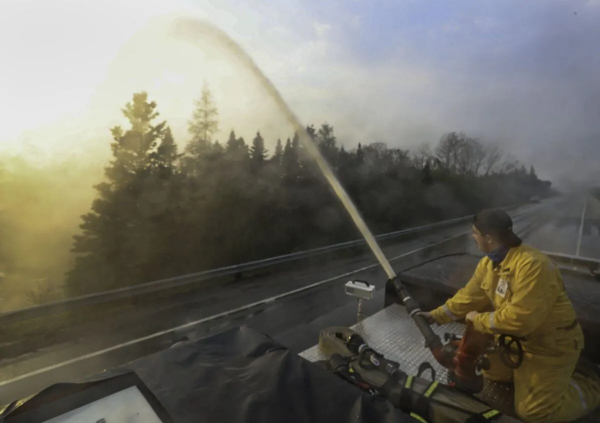 Northfield fire department member Seth Slauenwhite sprays down a flare up along Highway 103, near Shelburne, N.S., in this June 3, 2023, handout photo. (The Canadian Press/HO-Communications Nova Scotia)
