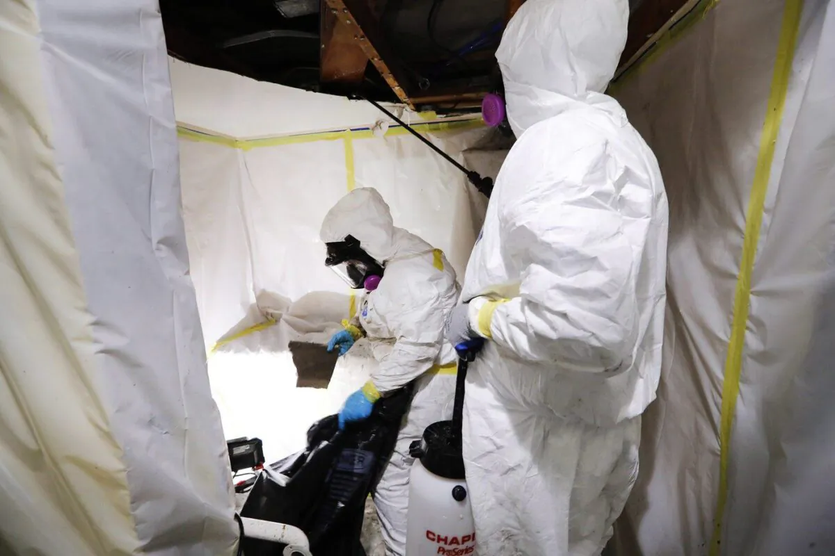 Asbestos Removal Technologies Inc., superintendent Ryan Laitila, right, sprays amended water, as Megan Eberhart bags ceiling material during asbestos abatement in Howell, Mich., October 18, 2017. (The Canadian Press/AP-Paul Sancya)
