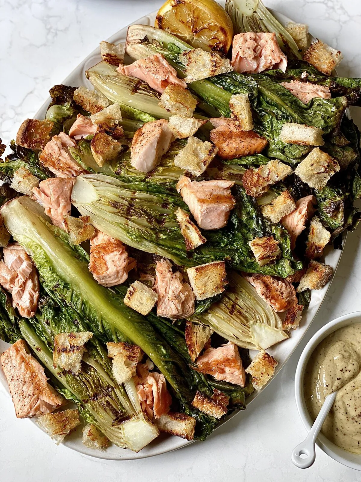 Every component of this leveled-up Caesar salad, from the romaine and salmon to the lemon and croutons, is cooked on the grill. (Kelli Foster/TNS)