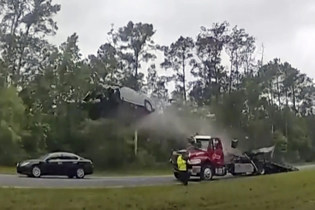 A vehicle goes airborne after driving up the ramp of a flatbed tow truck on a highway in Lowendes County, Ga., on May 24, 2023, in a still from police body camera video. (Lowndes County Sheriff's Office via AP)