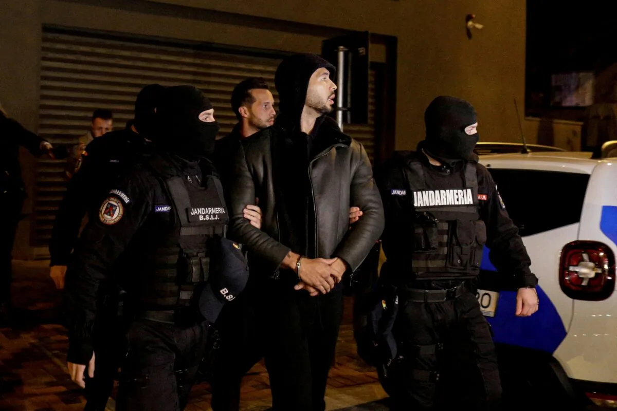 Andrew Tate and Tristan Tate are escorted by police officers outside the headquarters of the Directorate for Investigating Organized Crime and Terrorism in Bucharest (DIICOT) after being detained for 24 hours, in Bucharest, Romania, on Dec. 29, 2022. (Inquam Photos/Octav Ganea via Reuters)