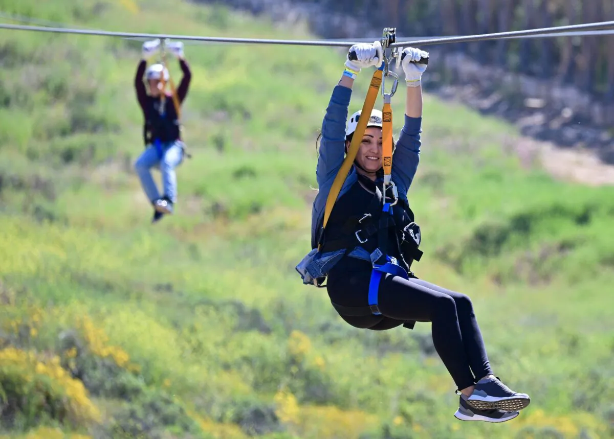 People hold on while ziplining over blooming wildflowers at Skull Canyon Ziplines in Corona, Calif., on April 11, 2023. (Frederic J. Brown/AFP via Getty Images)