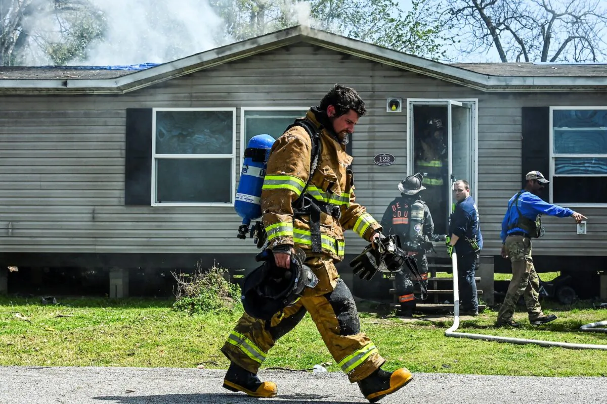 A firefighter walks past the damaged house of Andrea Larry as it catches fire in Rolling Fork, Miss., after a tornado touched down in the area, on March 26, 2023. (Chandan Khanna/AFP via Getty Images) 