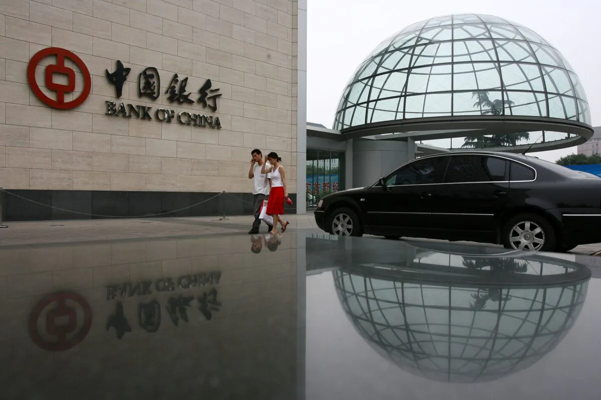 A couple walk past the headquarters of Bank of China, the country's second-largest lender in Beijing, China, on June 28, 2006. (China Photos/Getty Images)