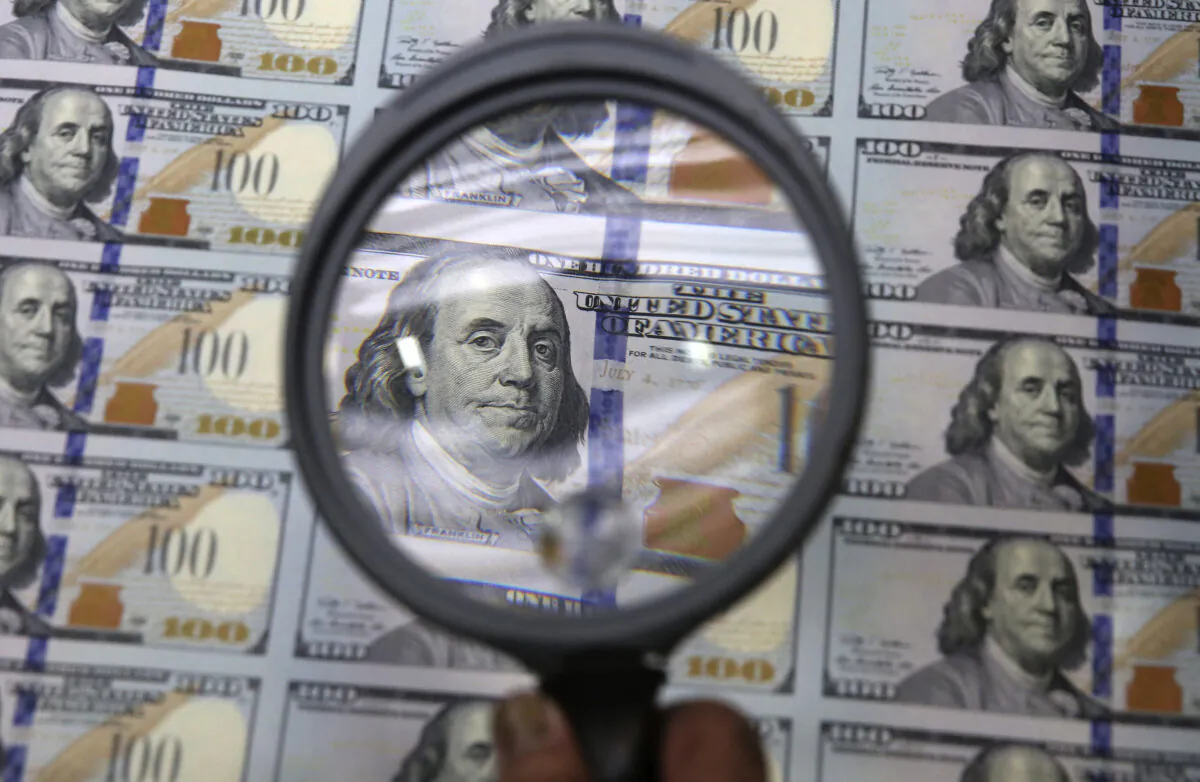 A sheet of uncut $100 bills is inspected during the printing process at the Bureau of Engraving and Printing Western Currency Facility in Fort Worth, Texas, on Sept. 24, 2013. (LM Otero/AP Photo)