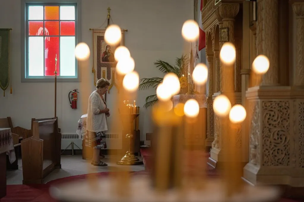 A woman pauses after lighting a candle before Sunday service at St. George's Ukrainian Orthodox Church, in Dauphin, Man., on June 18, 2023. (The Canadian Press/Darryl Dyck)