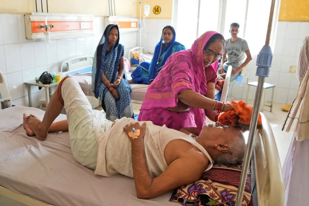Shiela Mishra wipes the head of her ailing brother to keep him cool from the heat wave by using a wet cloth at the district hospital in Ballia, Uttar Pradesh state, India, on June 19, 2023. (Rajesh Kumar Singh/AP Photo)