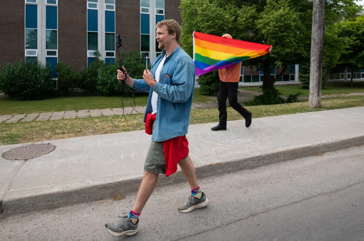 A protester against Pride Month celebrations records a video as a counter-protester holds a rainbow flag during a protest between Pride supporters and opponents near schools in Ottawa's west end on June 9, 2023. (The Canadian Press/Spencer Colby)