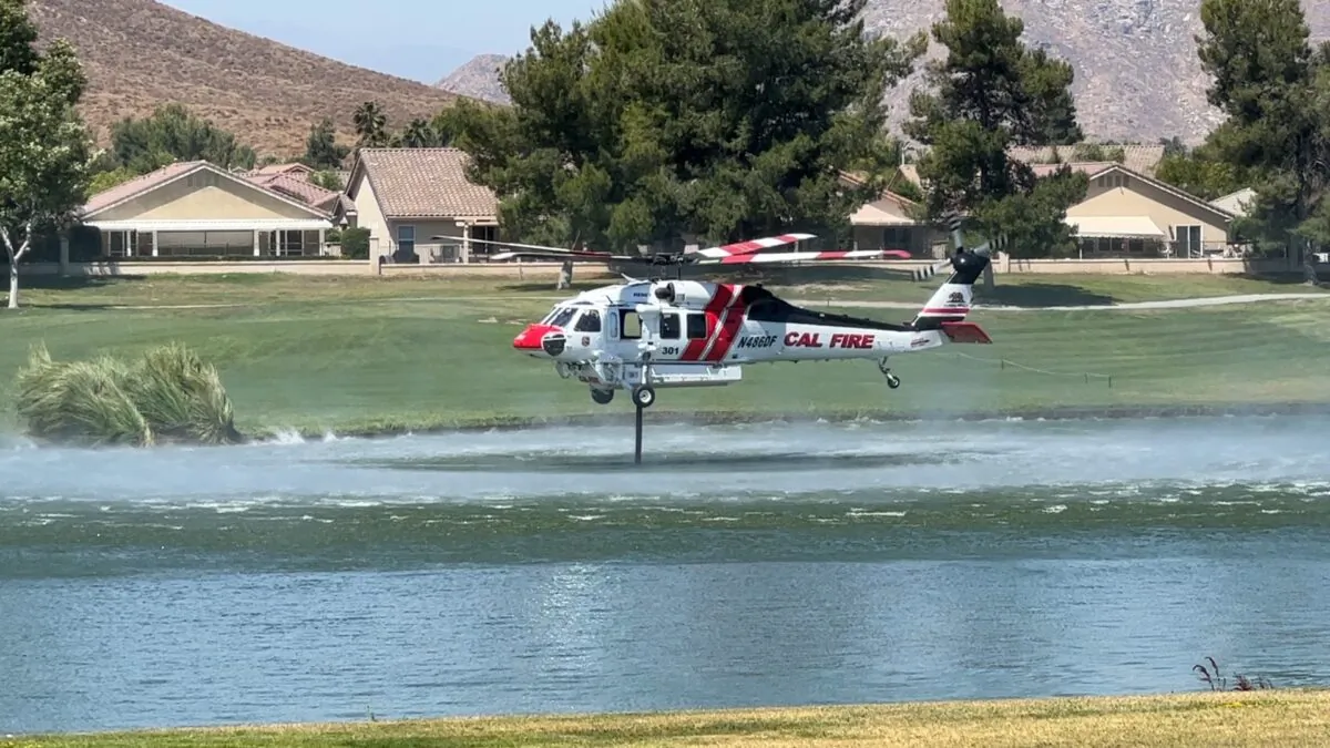 A CAL FIRE helicopter picks up water from the Palms Golf Course at Menifee Lakes Country Club to extinguish a brush fire in Menifee, Calif., on June 20, 2023. (Brad Jones/The Epoch Times)