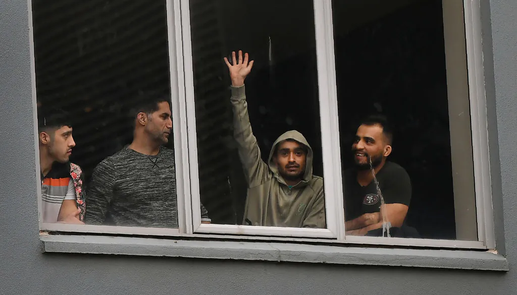 Asylum seekers gesture to protesters holding a pro-refugee rights rally from their hotel room where they have been detained in Melbourne on June 13, 2020. (William West/AFP via Getty Images)