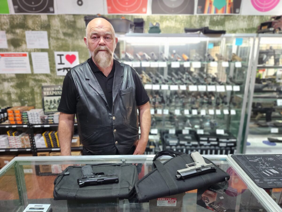 Tom Van Hoose, owner of Highwood Creek Outfitters in Grand Falls, Mont., shows a pair of semi-automatic handguns on June 20, 2023. (Allan Stein/The Epoch Times)