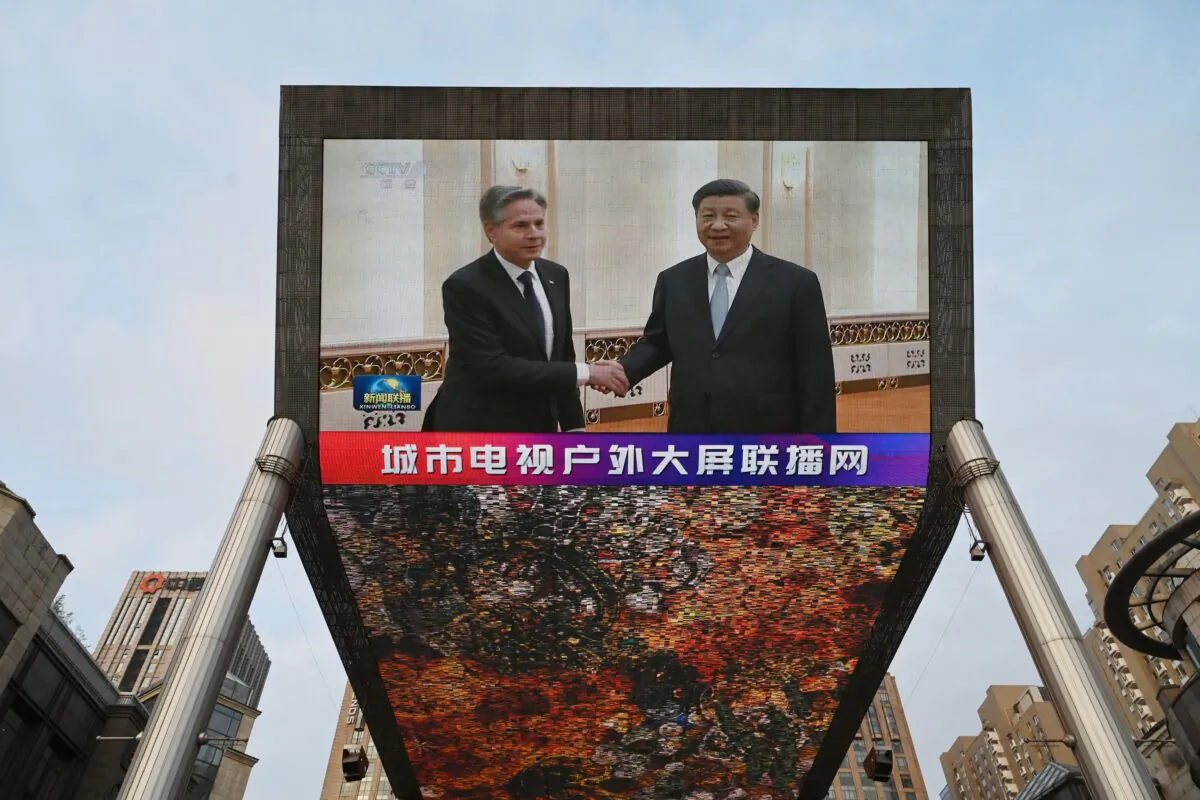 A China Central Television news broadcast shows footage of U.S. Secretary of State Antony Blinken meeting with Chinese leader Xi Jinping, on a giant screen outside a shopping mall in Beijing on June 19, 2023. (Greg Baker/AFP via Getty Images)