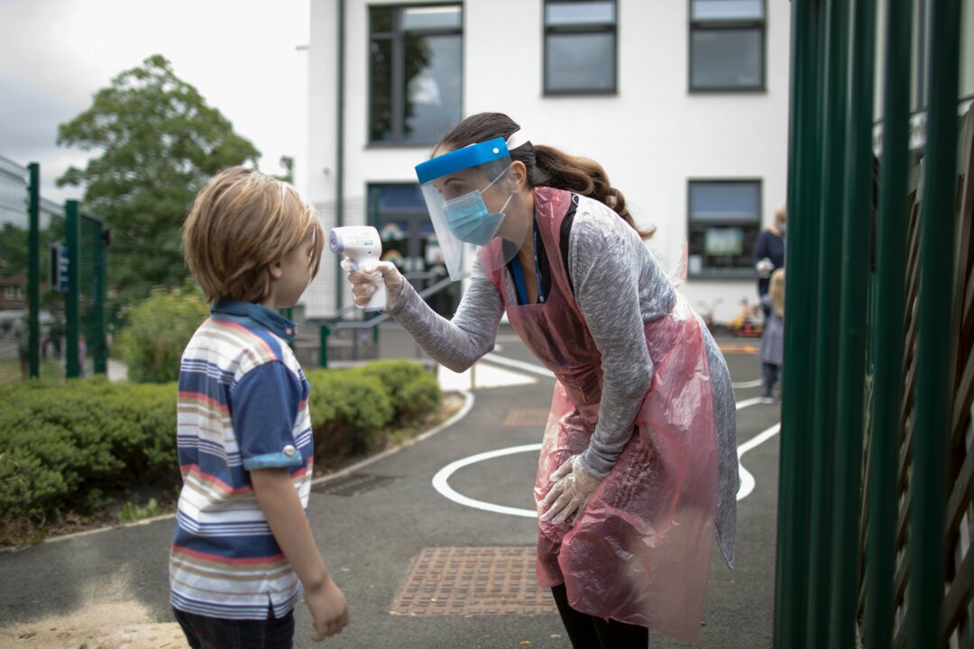 A member of staff wearing personal protective equipment takes a child's temperature at the Harris Academy's Shortland's school in London on June 4, 2020. (Dan Kitwood/Getty Images)