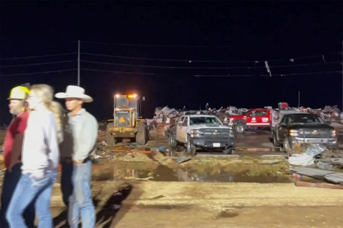 People stand near debris in Matador, Texas, on June 21, 2023, following storms went through the area. (KAMC/KLBK via AP)