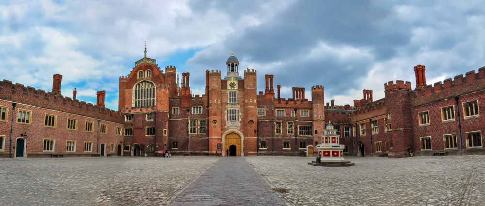 The western façade of Hampton Court was built in the Tudor style, with its red brick, rows of rectangular windows, set of chimneys, and elaborate rooftops featuring gables. The façade features handmade bricks, tiles, stone, timber, and lead. Vitrified bricks form the large crisscross pattern that decorates the palace courtyard. At the center of the building is Anne Boleyn’s gatehouse, with an elaborate octagonal Tudor wine fountain on the right. (Mistervlad/Shutterstock)