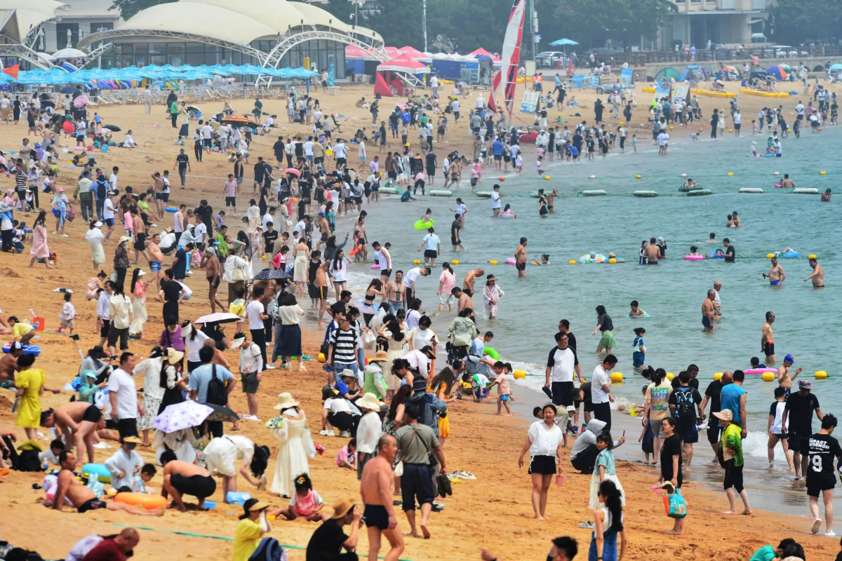 People cooling off on a beach amid hot weather in Qingdao, Shandong Province, China, on June 24, 2023. (STR/AFP via Getty Images)