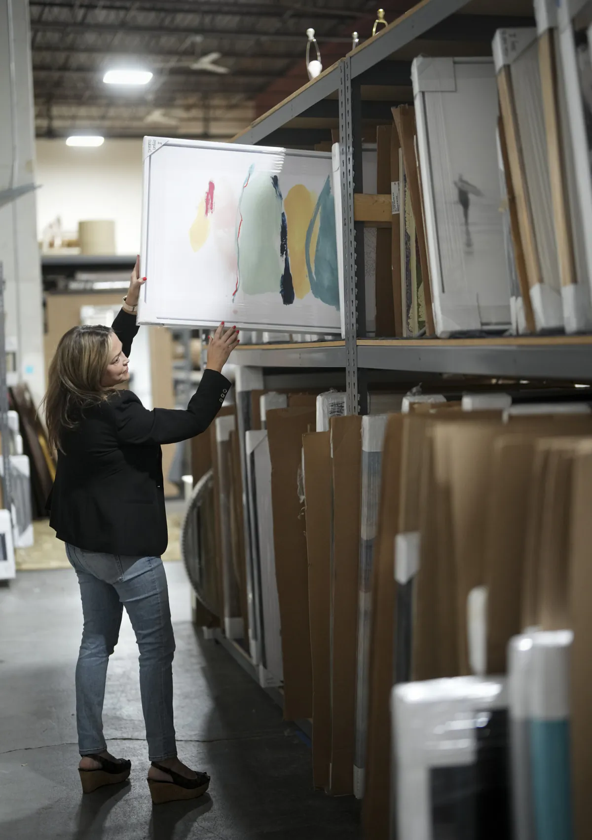 Laurie Flemming looks at art in the warehouse of her home staging company Fix Design Haus in Plymouth, Minnesota, on June 5, 2023. (Renée Jones Schneider/Minneapolis Star Tribune/TNS)