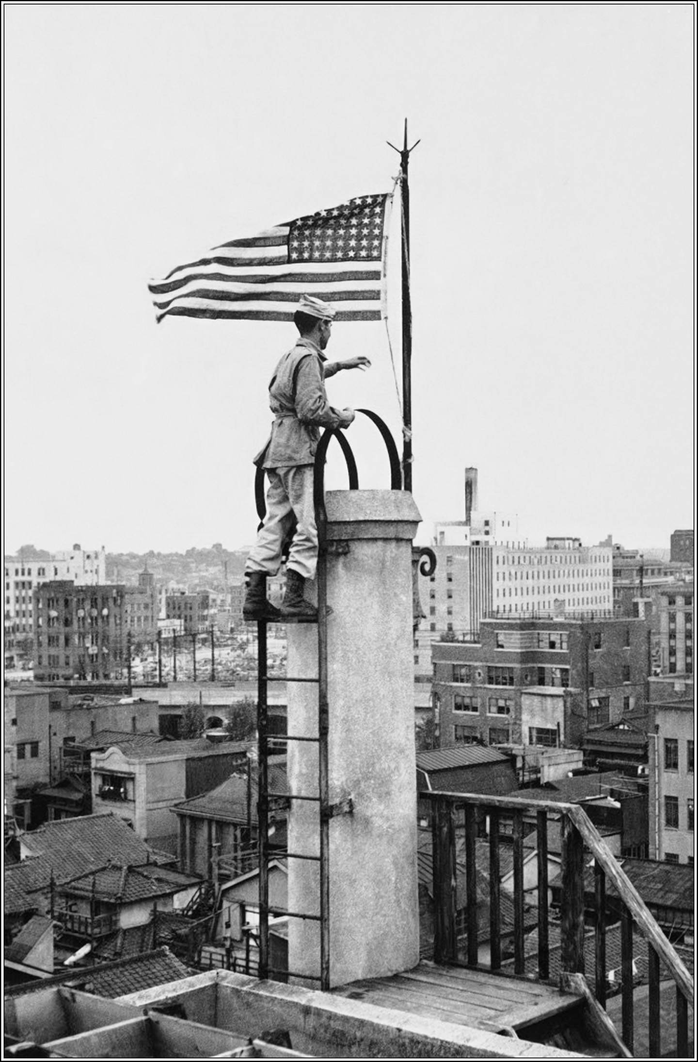 The Angels’ Lieutenant Bernard J. ‘Bud’ Stapleton raises the American flag atop the Nippon News building in Tokyo on September 5, 1945