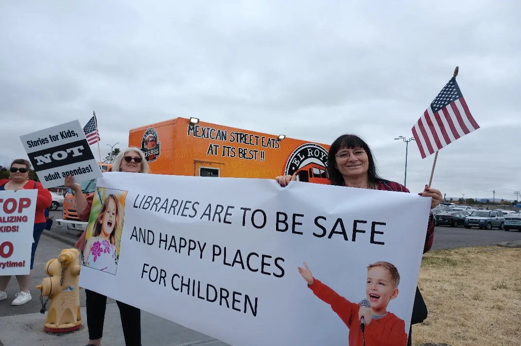 Protesters hold signs and banners along a busy street in front of the Petaluma Public Library. (Photo courtesy of Orlean Koehle)