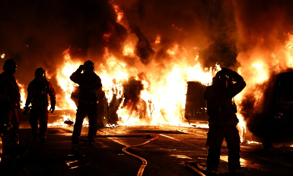 Firefighters stand as they extinguish burning vehicles during clashes between protesters and police, after the death of Nahel, a 17-year-old teenager killed by a French police officer during a traffic stop, in Nanterre, Paris suburb, France, on June 28, 2023. (Stephanie Lecocq/Reuters)