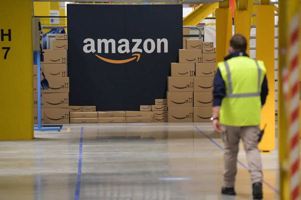 An Amazon employee passes by the company's logo on the opening day of the new distribution center in Augny, France, on Sept. 23, 2021. (SEBASTIEN BOZON/AFP via Getty Images)