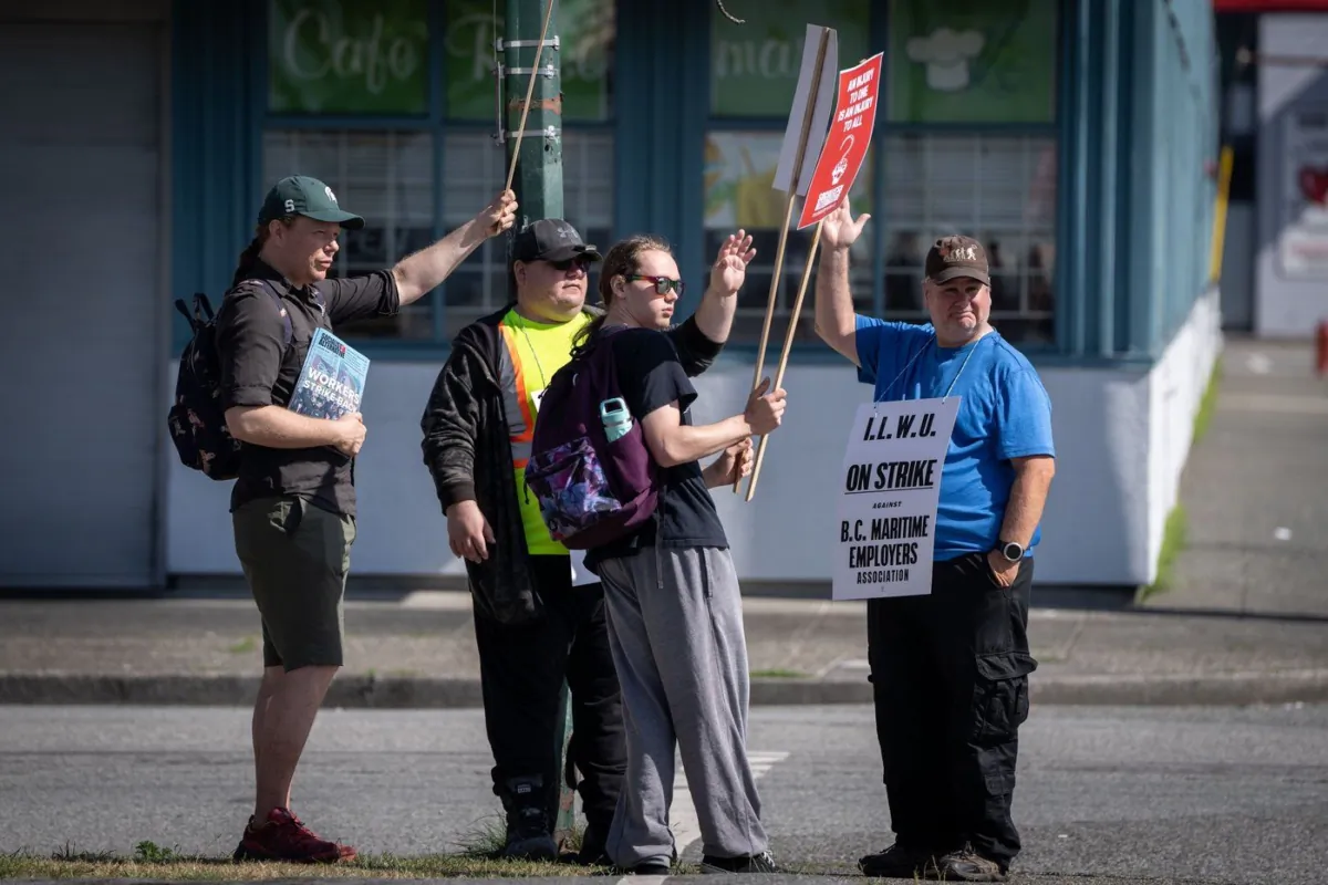 International Longshore and Warehouse Union workers wave at cars driving past while picketing outside of the BC Maritime Employers Association Dispatch Centre after a 72-hour strike notice and no agreement made at the bargaining table, in Vancouver on July 1, 2023. (The Canadian Press/Ethan Cairns)