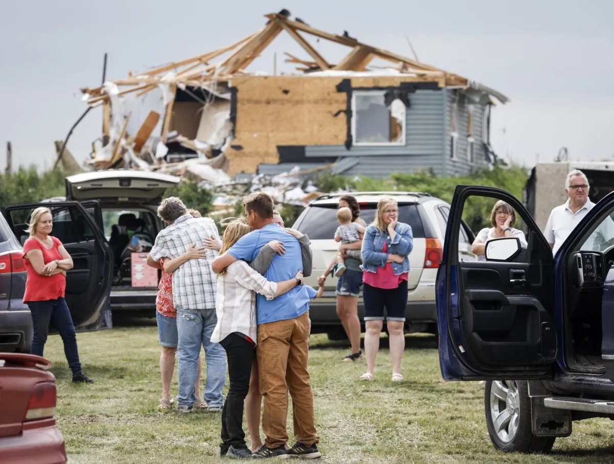 People embrace after a tornado damaged homes near Carstairs, Alta., July 1, 2023. (The Canadian Press/Jeff McIntosh)
