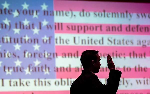 The oath of office is projected on a screen behind an ROTC cadet as he takes the oath. (Photo by Ken Scar)