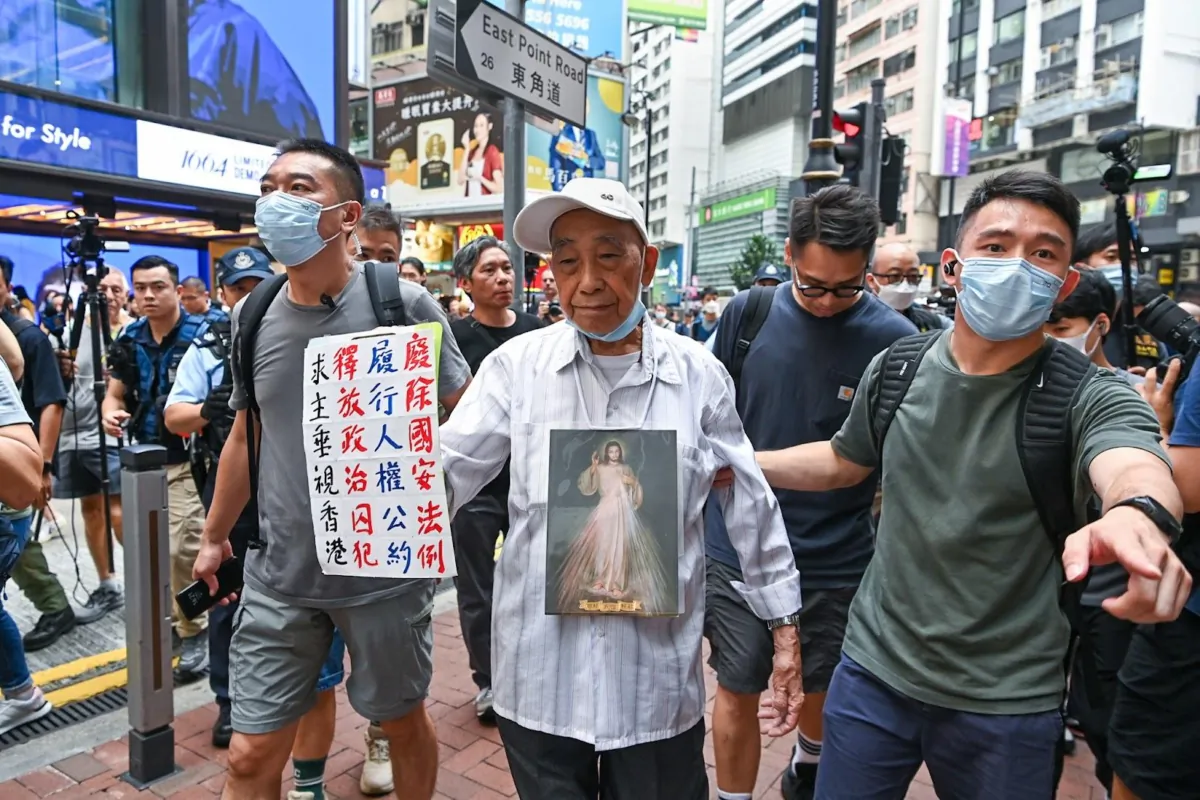 87-year-old “Uncle Ng” was surrounded by a number of police officers and escorted to the Causeway Bay MTR station after holding a sign that read "Abolish national security laws, implement human rights conventions, release political prisoners, and may God bless Hong Kong." July 1, 2023. (Sung Pi-Lung/The Epoch Times)