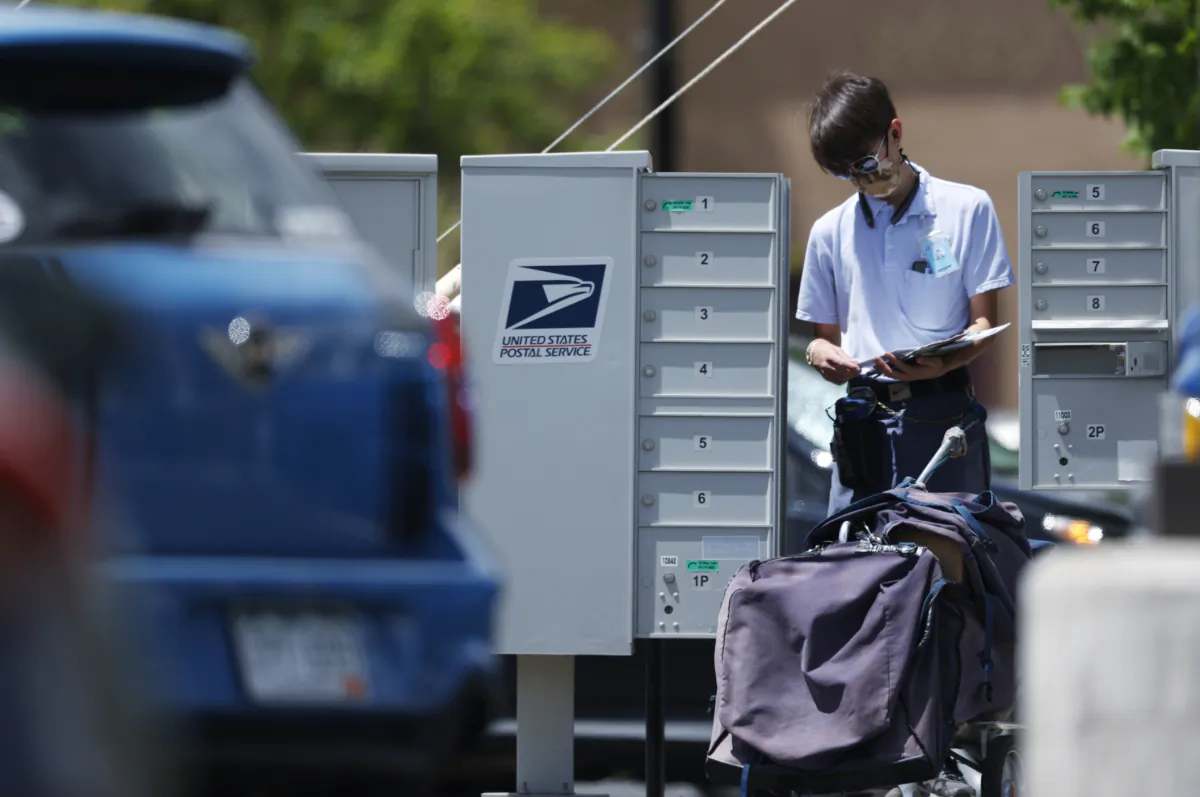 A mailman wears a face mask while completing his route in Littleton, Colo., on May 23, 2020. (David Zalubowski/AP Photo) 