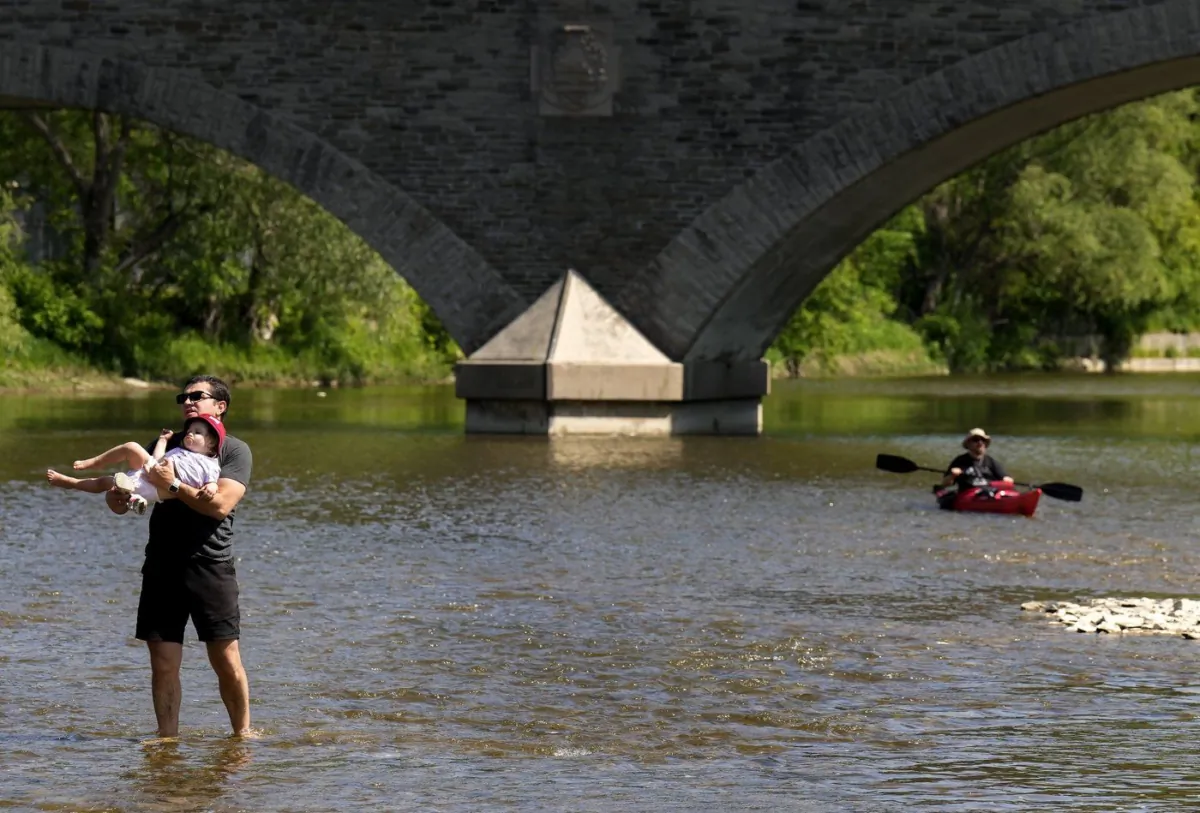 People enjoy the cool water along Humber River on a warm sunny day in Toronto on May 29, 2023. (The Canadian Press/Nathan Denette)
