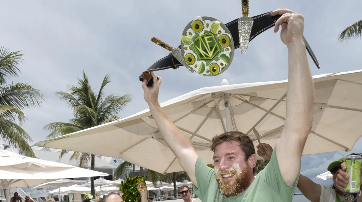 Joshua Mogle raises the winner's belt after devouring a 9-inch Key lime pie at the World Famous Key Lime Pie Eating Championship in Key West, Fla., on July 4, 2023. (Rob O'Neal/Florida Keys News Bureau via AP)