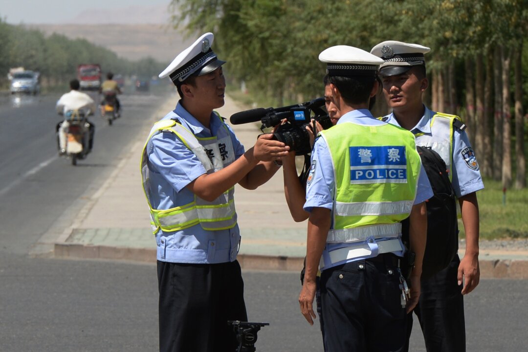 Chinese police detain a journalist at a checkpoint on the road to the riot-affected Uyghur town of Lukqun, Xinjiang region, on June 28, 2013. (Mark Ralston/AFP via Getty Images)