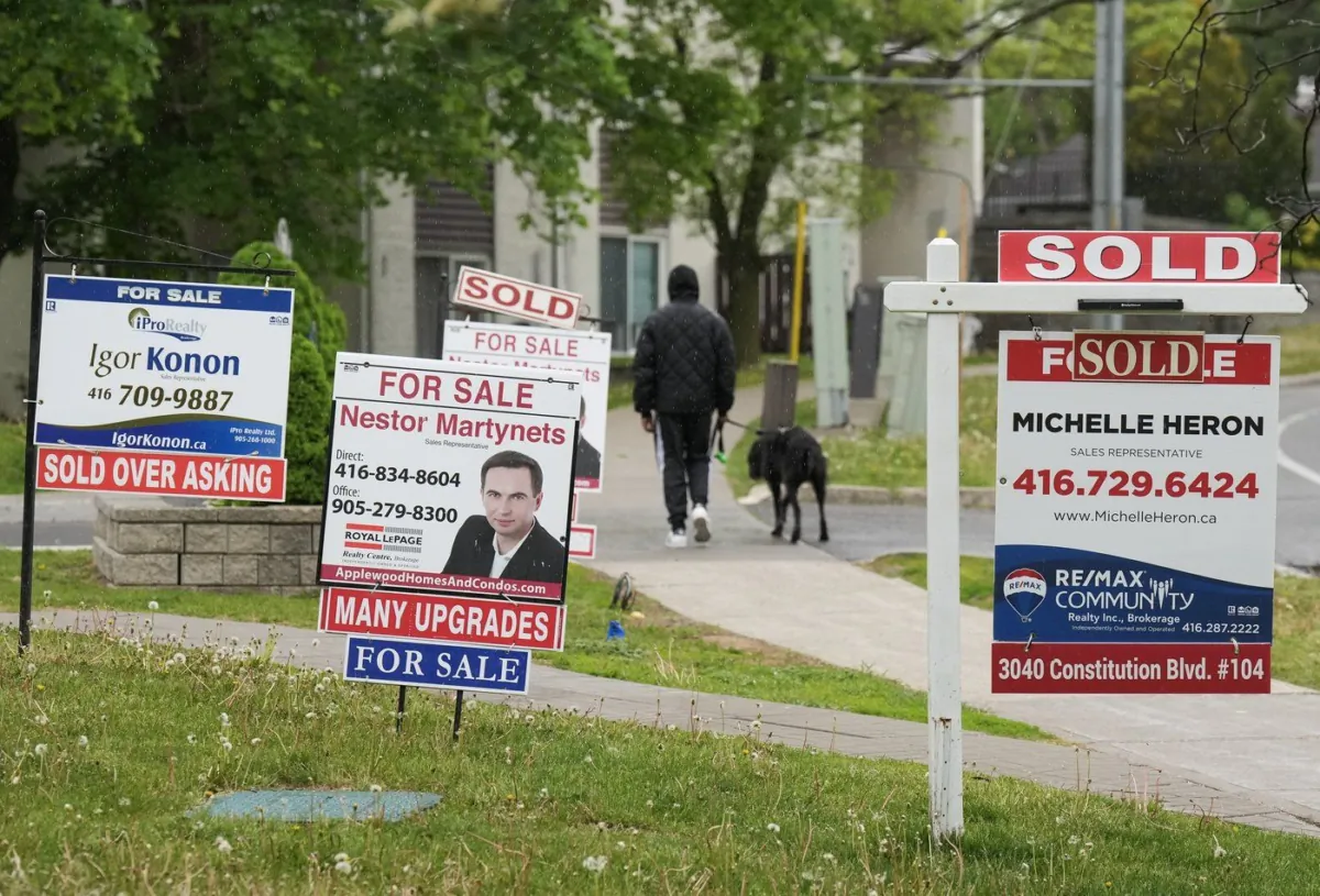 A person walks past multiple for-sale and sold real estate signs in Mississauga, Ont., on May 24, 2023. (The Canadian Press/Nathan Denette)