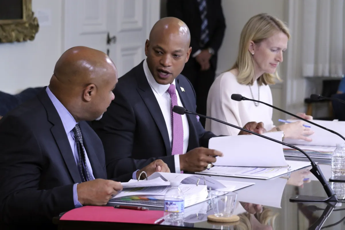 Maryland Gov. Wes Moore (C) talks to Treasurer Dereck Davis during a meeting of the Board of Public Works, which approved $2.9 million in compensation for John Huffington, in Annapolis, Md., on July 5, 2023. (Brian Witte/AP Photo)