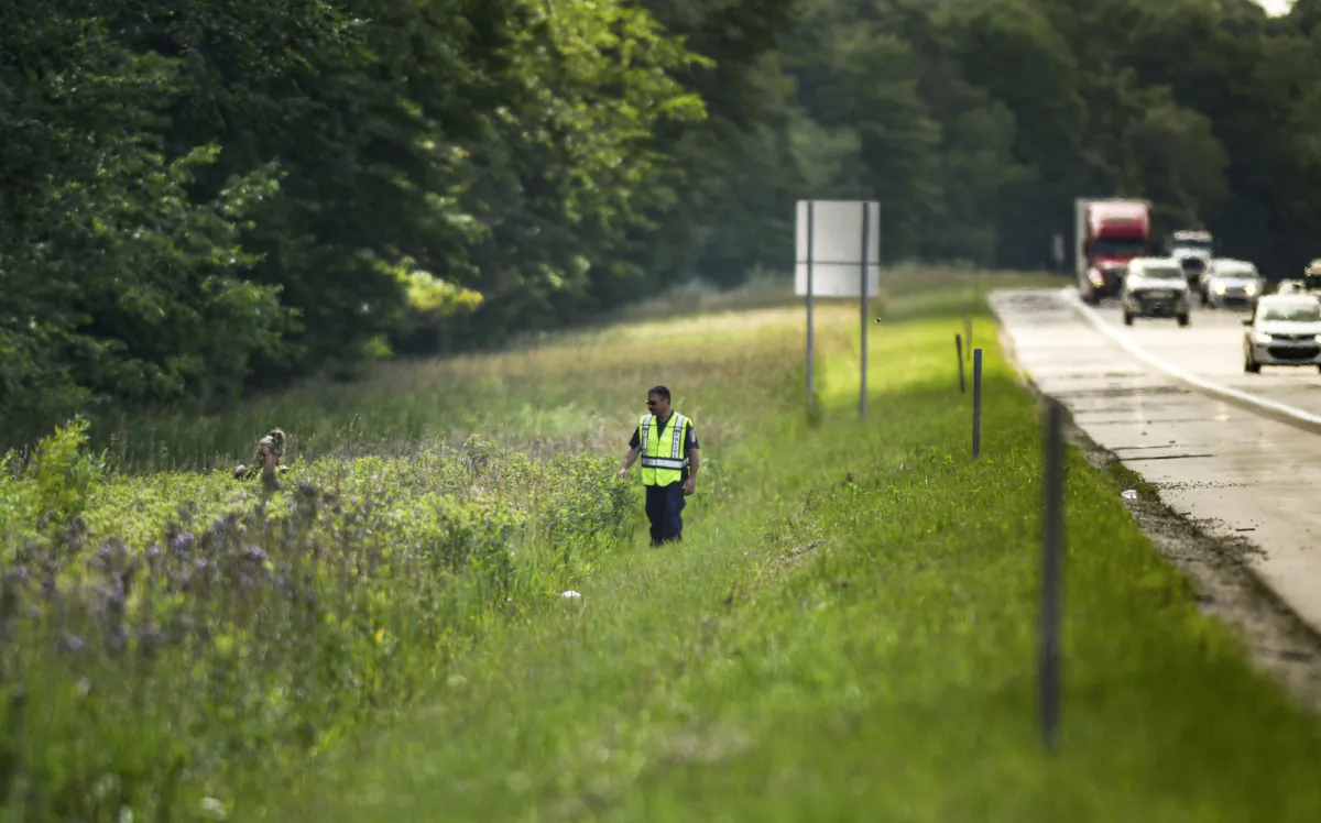 Lansing Police Detective Pete Scheccia (R) and another LPD member search an area along eastbound Interstate 96 near the Williamston Road exit between Lansing, Mich., and Detroit on July 5, 2023. (Matthew Dae Smith/Lansing State Journal via AP)
