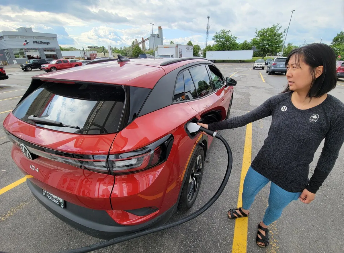 A woman checks the status of the charge for her 2022 Volkswagen ID.4 EV at a charging station at a Scarborough, Ontario Canadian Tire on June 14, 2023. (The Canadian Press/Doug Ives)
