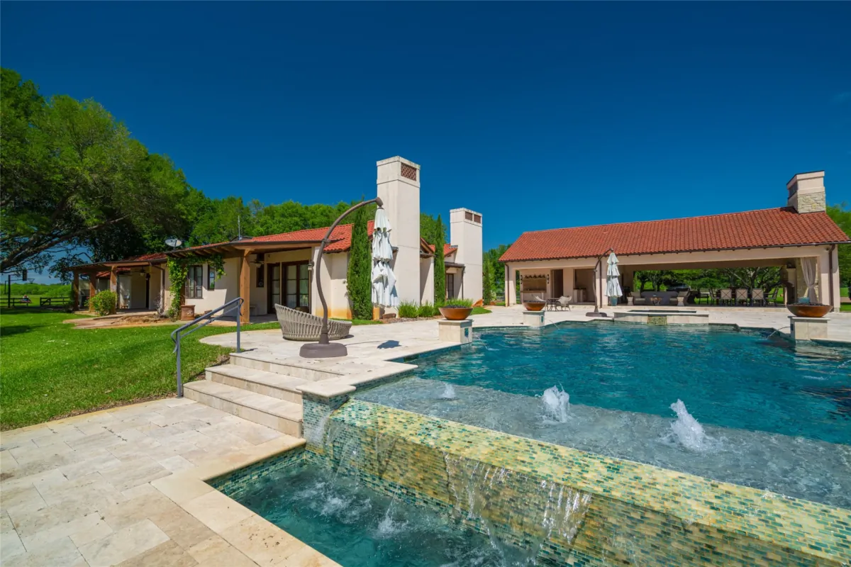 An oversized infinity pool with a covered area, full kitchen, and covered lounge area is located between the main house and the spacious guest quarters. (Courtesy of Ragnar Fotografi / Sotheby’s Int’l Realty)