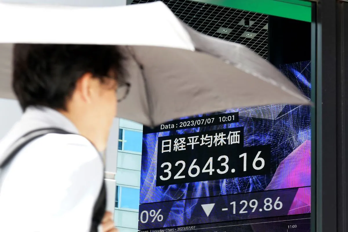A person walks in front of an electronic stock board showing Japan's Nikkei 225 index at a securities firm in Tokyo on July 7, 2023. (Eugene Hoshiko/AP Photo)
