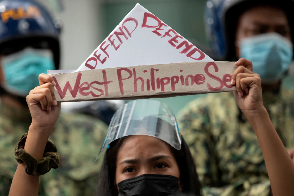 An activist holds a prop with the words "defend West Philippine Sea" during a protest outside the Chinese Consulate in Manila's financial district, guarded by Philippine police, on the anniversary of an international arbitral court ruling invalidating Beijing's historical claims over the waters of the South China Sea in Makati City, Philippines, on July 12, 2021. (Eloisa Lopez/Reuters)