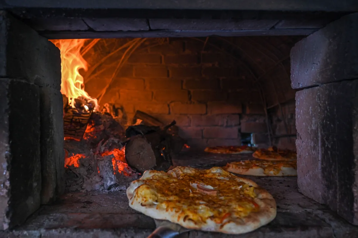 A pizzeria chef removes one of the freshly baked pizzas from a wood-fired oven at the Jemapoh Pizza Kayu Api restaurant in Jemapoh, in Malaysia's Negeri Sembilan state, on Nov. 5, 2020. (Mohd Rasfan/AFP via Getty Images)