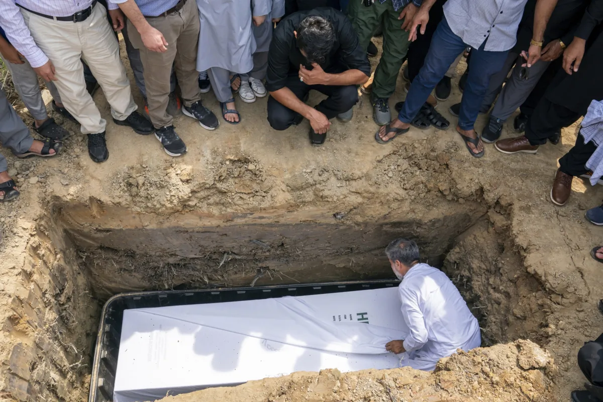 Friends and family watch as the body of Nasrat Ahmad Yar, 31, is placed into a grave during a funeral service at the All Muslim Association of America cemetery, in Fredericksburg, Va., on July 8, 2023. (AP Photo/Nathan Howard)