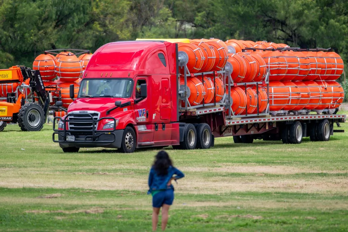 A woman surveys the preparation of a buoy barrier installation in Eagle Pass, Texas, on July 7, 2023. (Brandon Bell/Getty Images)