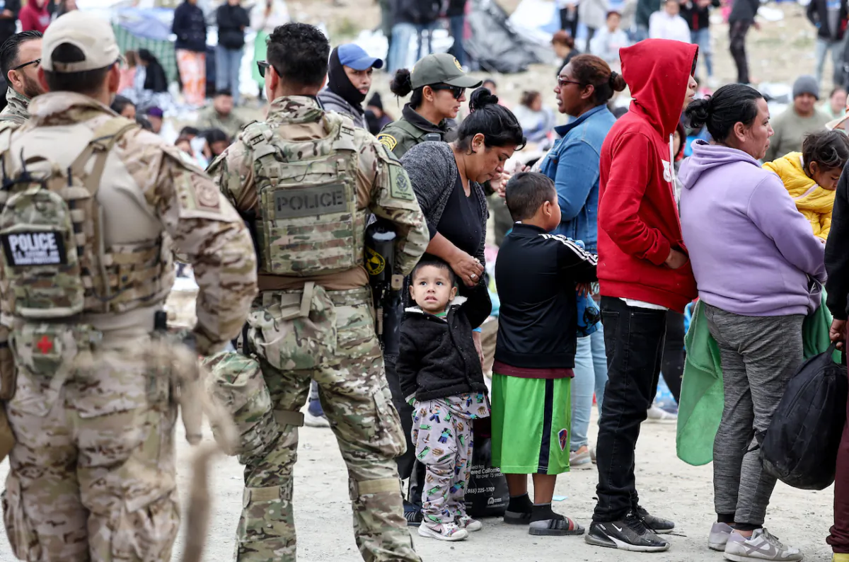 Federal law enforcement agents and officers keep watch as immigrants line up to be transported from a makeshift camp between border walls between the U.S. and Mexico in San Diego on May 13, 2023. (Mario Tama/Getty Images)