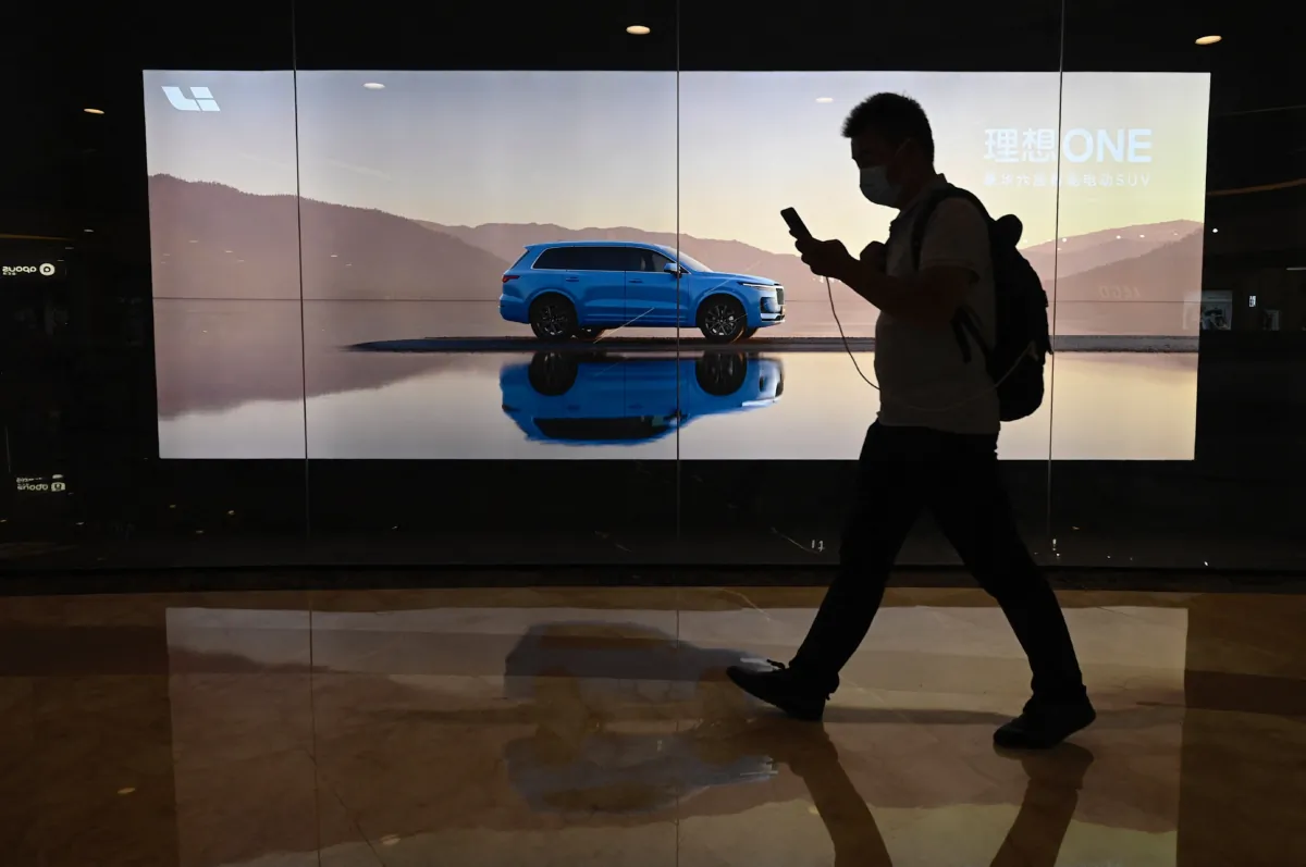A man walks past a billboard featuring a new model Li Xiang One by Chinese electric car maker Li Auto Inc. at a shopping mall in Beijing on Aug. 12, 2021. (JADE GAO/AFP via Getty Images)