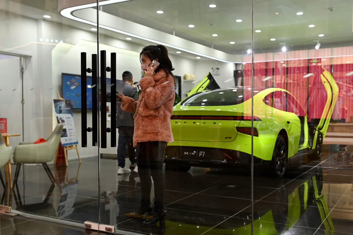A woman uses her phone in a Xiaopeng Motor showroom, a Chinese electric car manufacturer, in Beijing on March 19, 2021. (Wang Zhao/AFP via Getty Images)