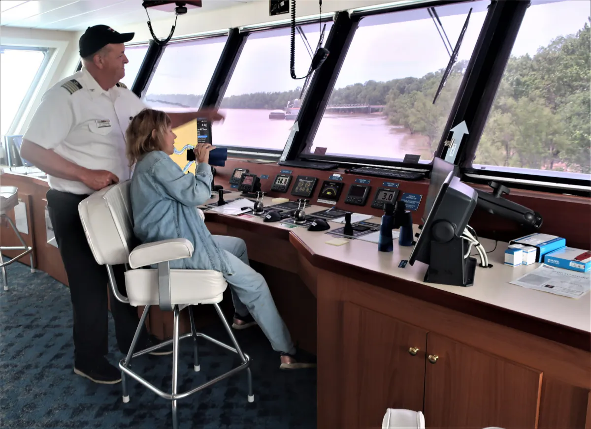 Fyllis Hockman takes a turn on the bridge with the captain of the American Symphony during a Mississippi River cruise. (Photo courtesy of Victor Block)